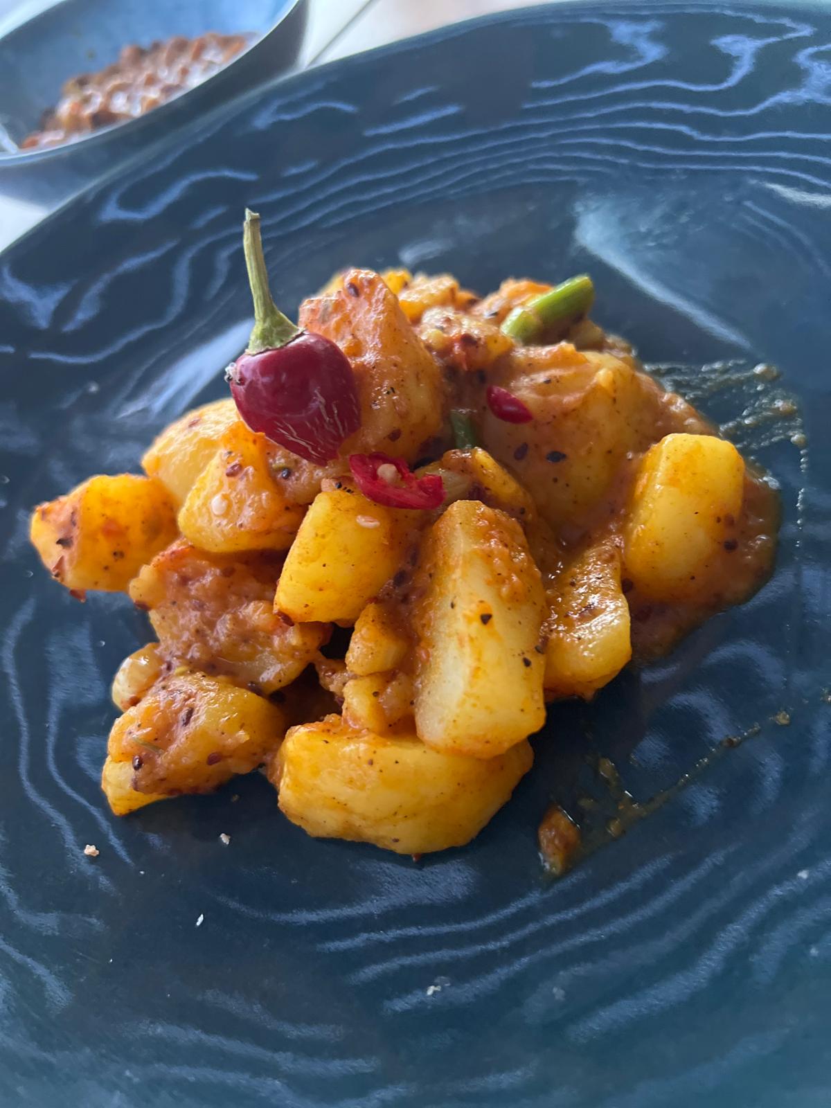 Ayurvedic potato curry with chilli on a dark plate