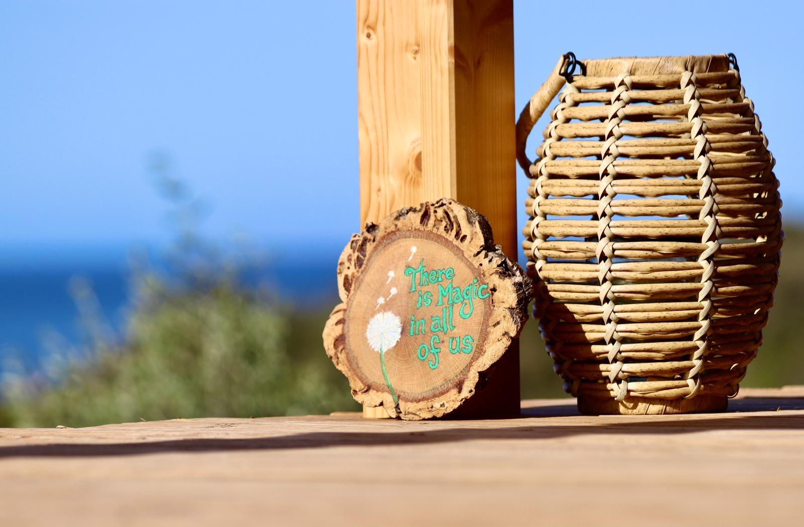 A painted slice of oak beside a woven lantern, above the sea